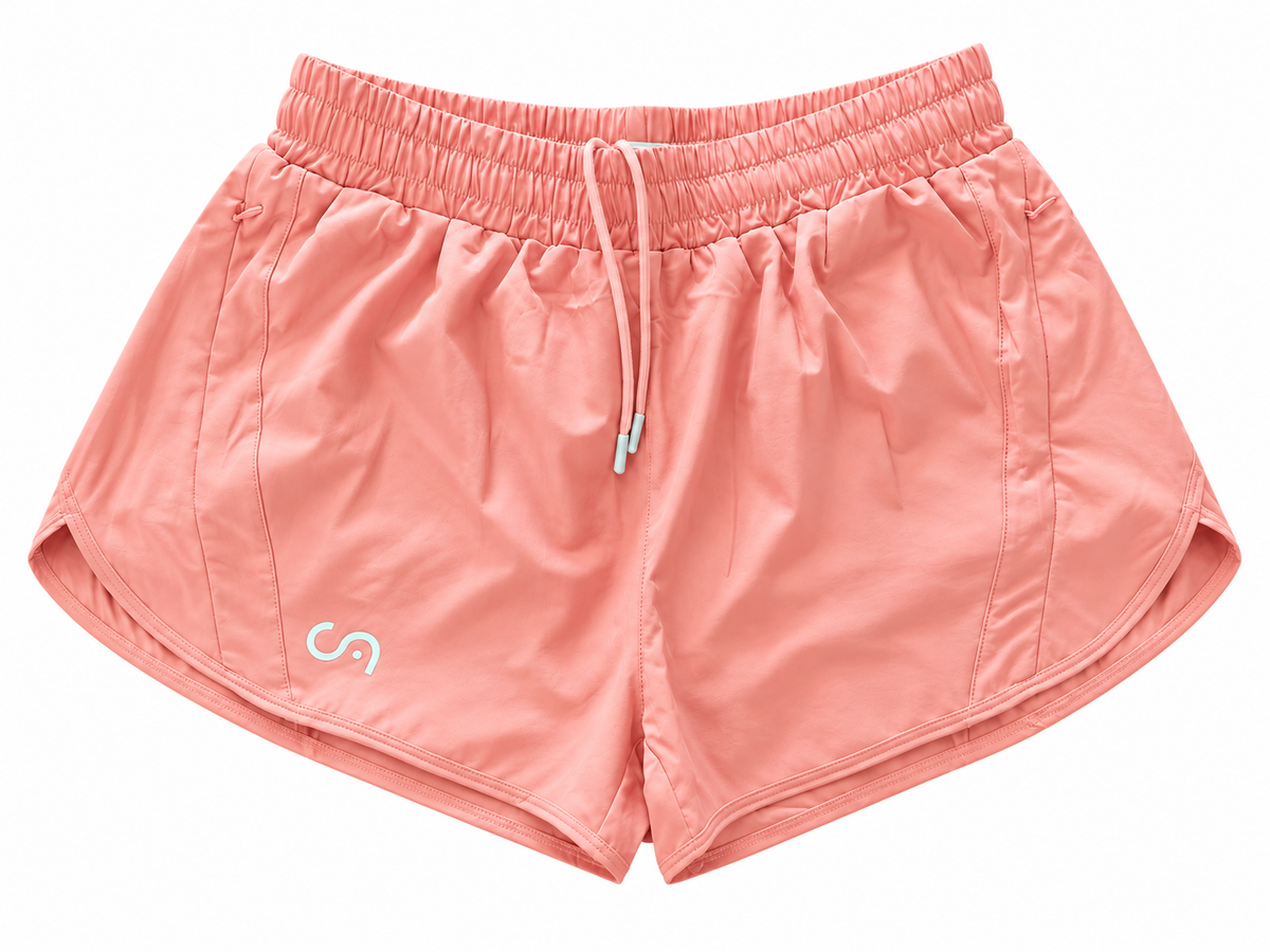A pair of peach pink athletic shorts with an elastic waistband, white drawstring, and a small white stylized logo on the lower left leg, shown against a plain white background.