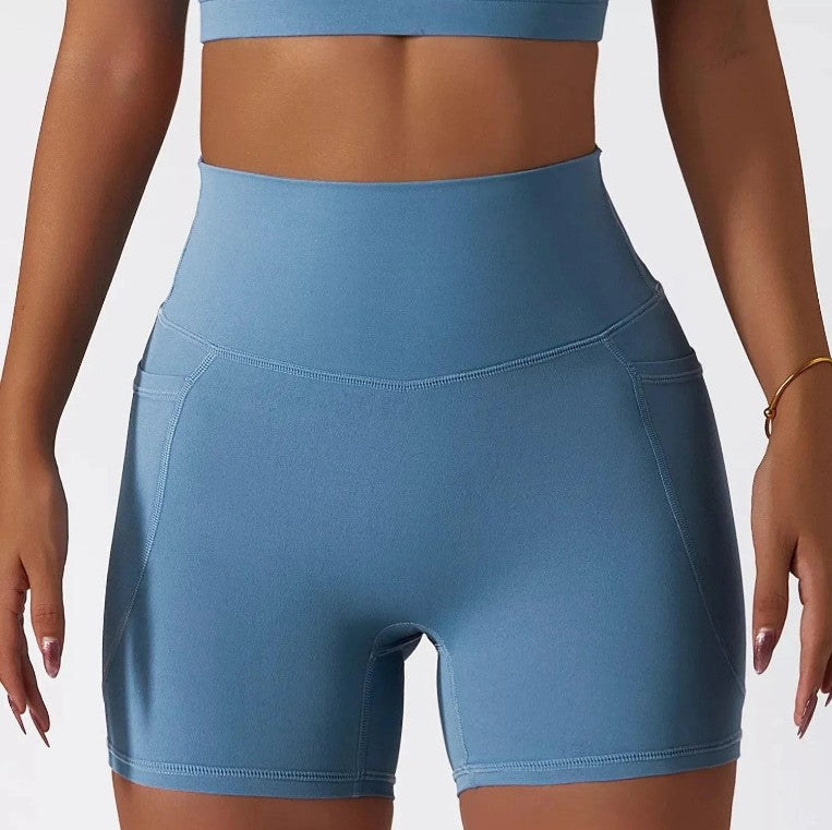 Woman wearing sky blue SECOND SKIN high-waisted shorts with side pockets by CAARDEO Active