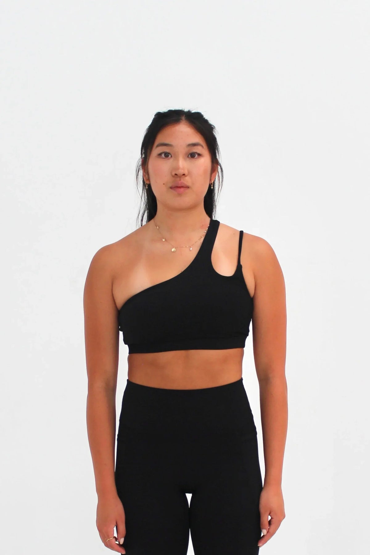Woman wearing black SECOND SKIN Louie asymmetric crop top by CAARDEO Active