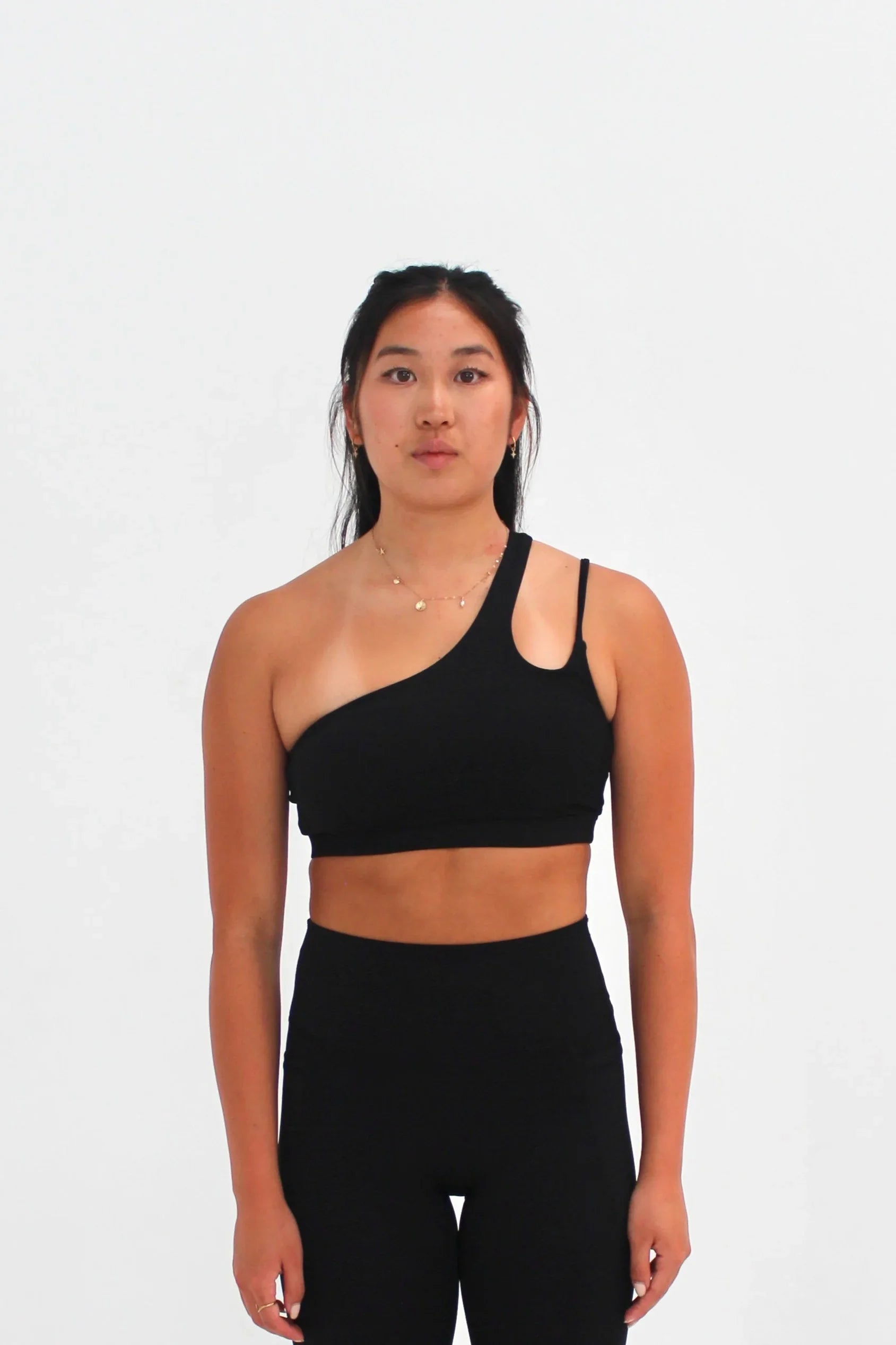 Woman wearing black SECOND SKIN Louie asymmetric crop top by CAARDEO Active