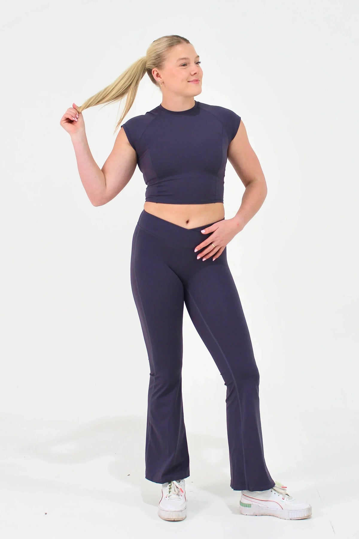 Woman wearing mauve high-waisted ELEVATE Flare Leggings by CAARDEO Active