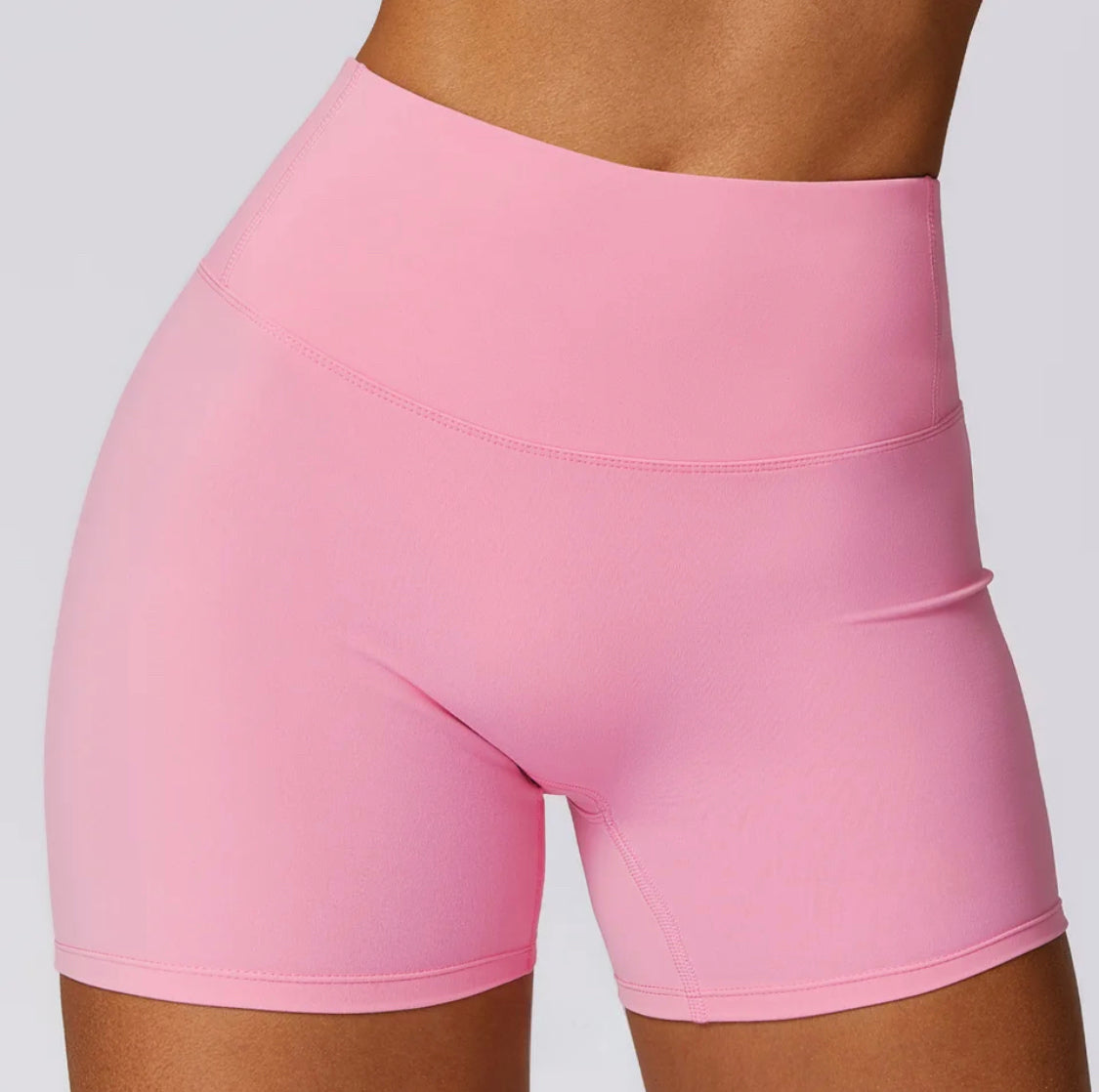 Woman wearing Spring Pink high-waisted SCULPT Shorts by CAARDEO Active
