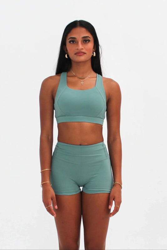 Woman wearing teal high-waisted SCULPT Shorts by CAARDEO Active