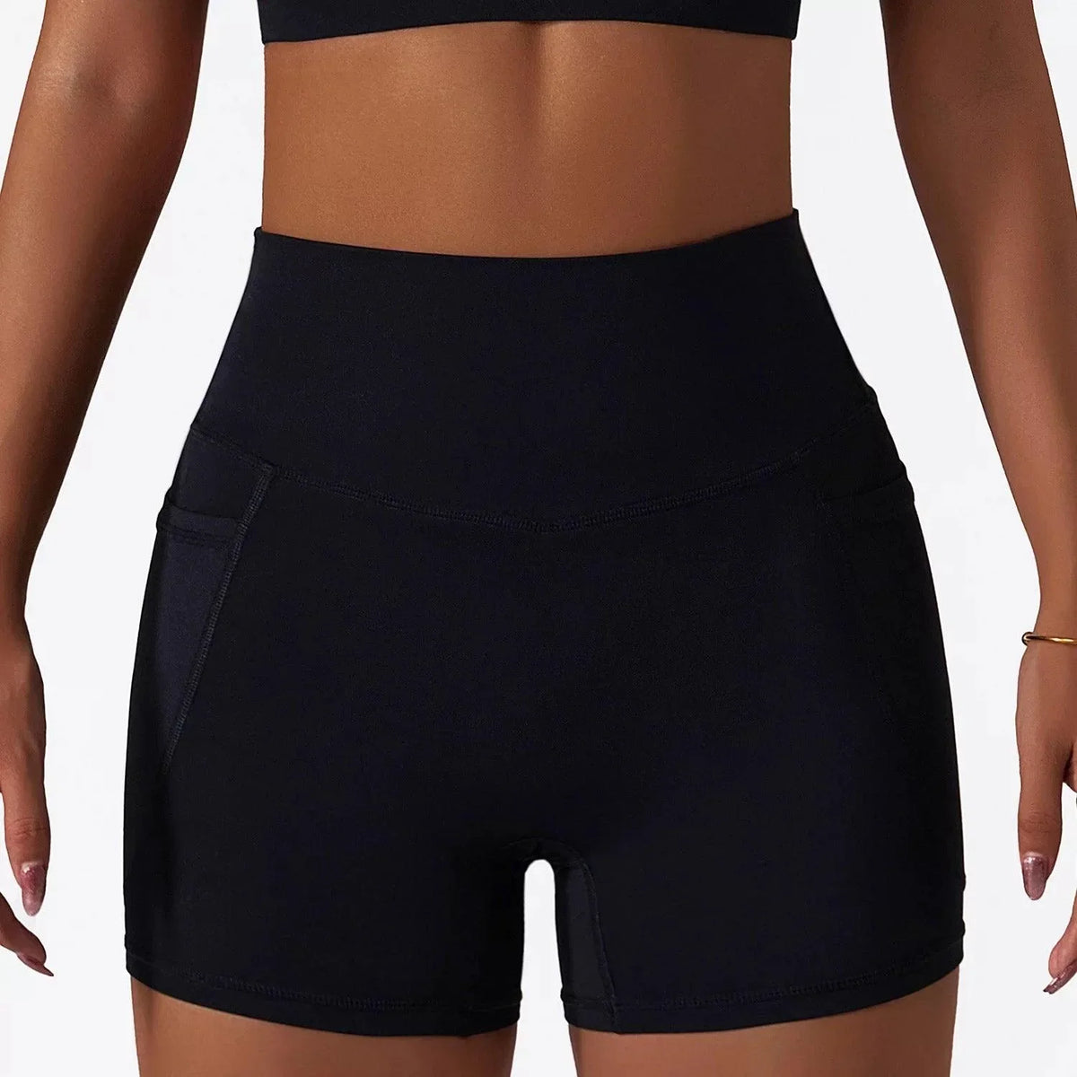Woman wearing black SECOND SKIN high-waisted shorts with side pockets by CAARDEO Active